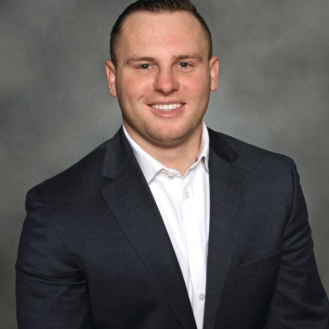 Photo of Trenton Hattler, a young man wearing an open collar shirt and a jacket